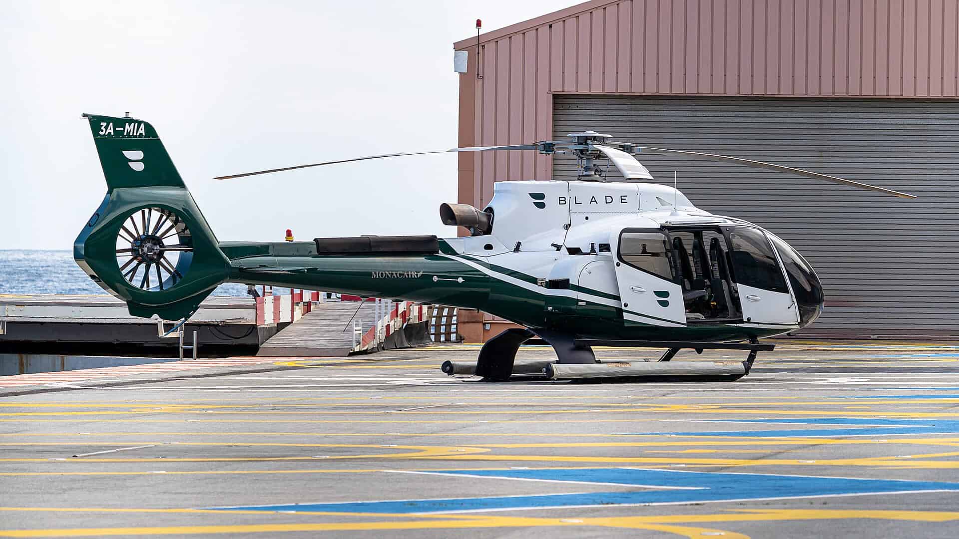 BLADE-branded Airbus H130 charter helicopter operated by Monacair parked on the Monaco Heliport pad