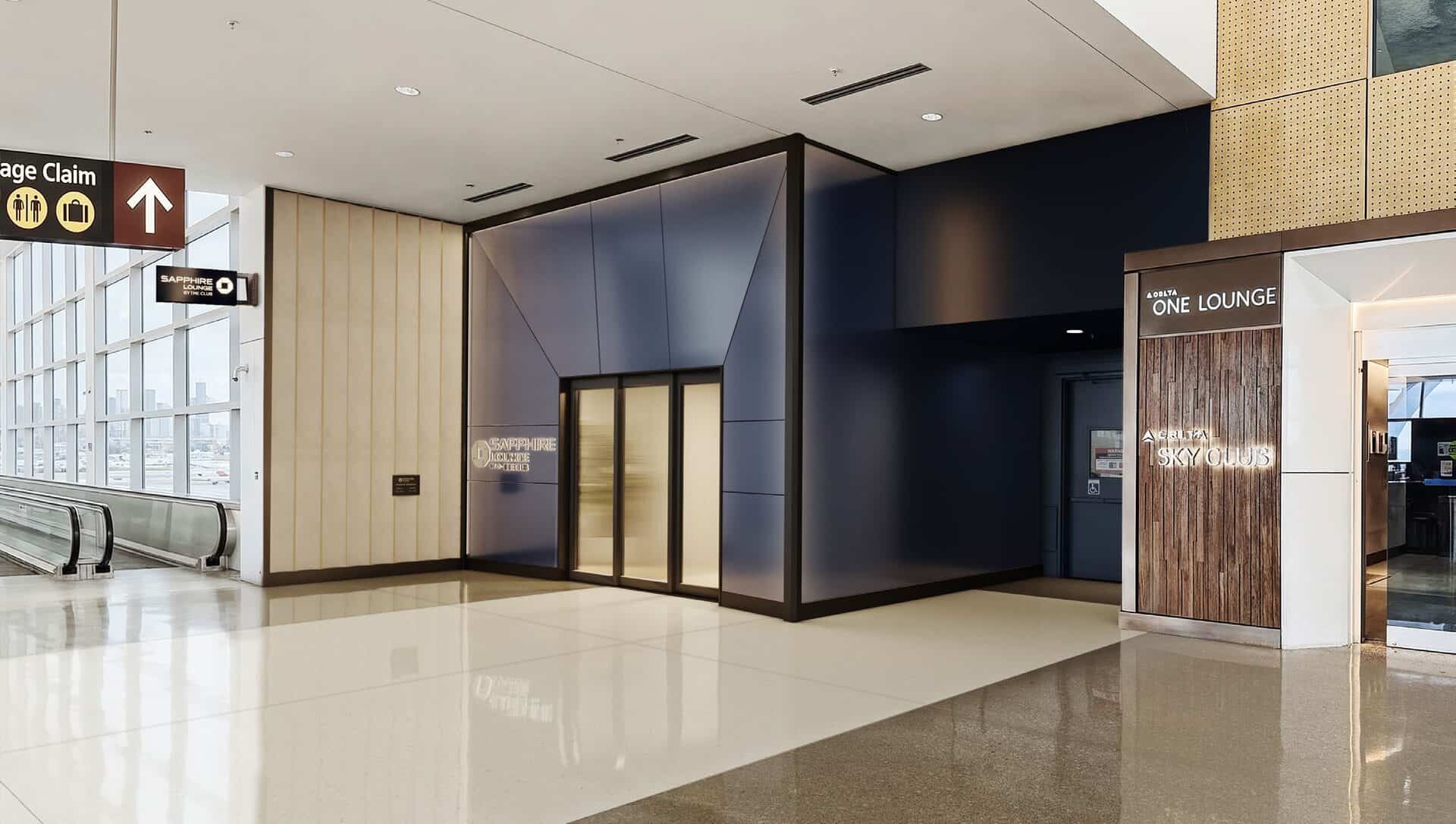 Rendering of the Chase Sapphire Lounge entrance on Sea-Tac Concourse A, a glass and dark-metal portal beside the Delta One Lounge and Delta Sky Club, with a moving walkway and airfield windows at left