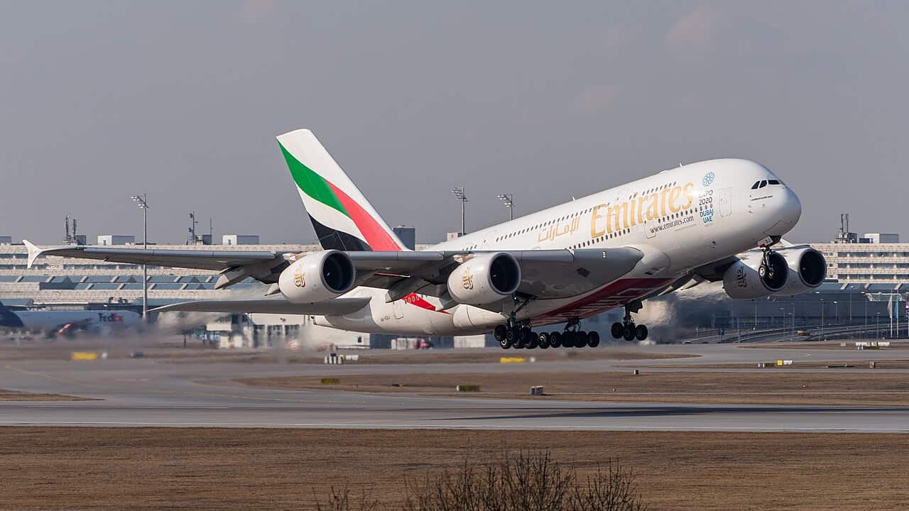 Emirates Airbus A380 lifting off from a runway with landing gear still extended, gold Emirates titles along the fuselage and the UAE flag livery on the tail